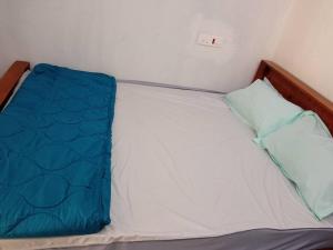 a small bed with a blue blanket on it at Sunset point view house. in Kovakulam