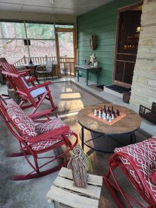 eine Terrasse mit einem Tisch, Stühlen und einem Schachbrett in der Unterkunft The White Conifer Cabin 