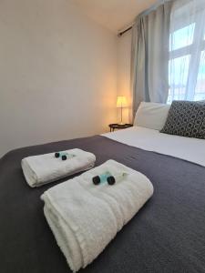- une chambre avec 2 lits et des serviettes à l'étage dans l'établissement Smart & Bright Apartment, à Londres
