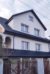 a white house with a black roof at Apartament u Anielki in Uniejow