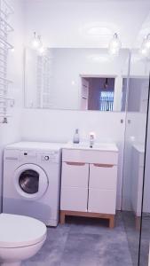a white bathroom with a washing machine and a toilet at Apartament u Anielki in Uniejow