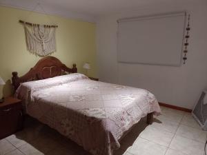 1 dormitorio con 1 cama con edredón blanco en Casa de huéspedes con pileta. en Villa Giardino