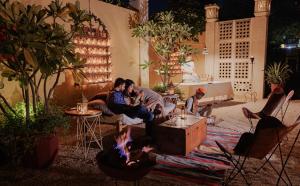 een groep mensen die rond een vuur in de woonkamer zitten bij The Ajit Bhawan - A Palace Resort in Jodhpur