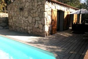 uma casa com piscina ao lado de um edifício de pedra em La Bergerie Nepita avec piscine pour 4 pers. em Porto-Vecchio