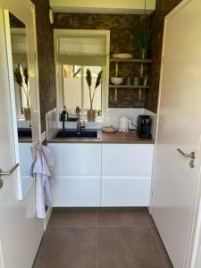 eine weiße Küche mit einem Waschbecken und einem Fenster in der Unterkunft Noflik Heerenveen in Heerenveen
