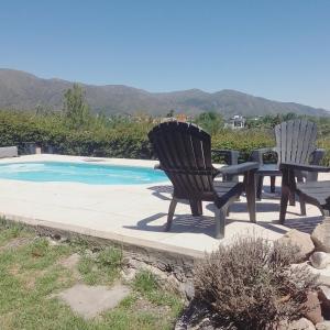 2 sillas y una mesa junto a la piscina en Casa de huéspedes con pileta. en Villa Giardino