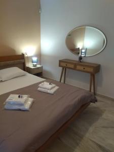 a bedroom with a bed with a mirror and two towels at Άνετο εξοχικό με ιδιωτικό χώρο στάθμευσης in Astrítsa