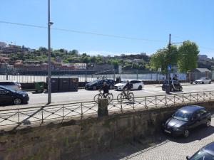 two people riding bikes on a road with cars at Happy Porto Hostel & Apartments in Porto