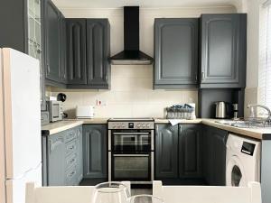 a kitchen with black cabinets and a stove at Windsor Cottage in Amble