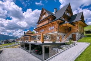 een groot houten huis met een terras rondom bij Widokowa Chata Kościelisko in Kościelisko