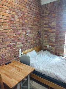 a room with a bed and a table and a brick wall at Studio Centrum Wejście na kod Code entry in Szczecin