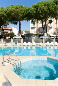 una grande piscina con sedie e alberi di Residence Quadrifoglio a Cervia