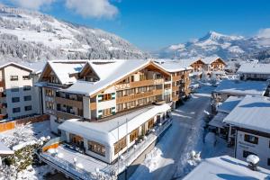 um resort nas montanhas com neve nos telhados em Alpen Glück Hotel Kirchberger Hof em Kirchberg in Tirol