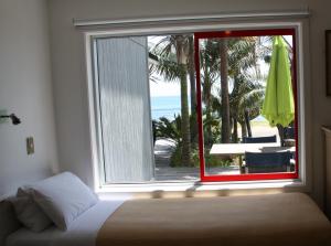 een slaapkamer met een raam met uitzicht op het strand bij Driftwood Beachfront Accommodation, Cable Bay, Owhetu in Coopers Beach