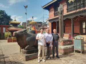 Un groupe de trois hommes debout à côté d'une statue dans l'établissement Kaji Chen, The Tourist Accommodation, à Pātan