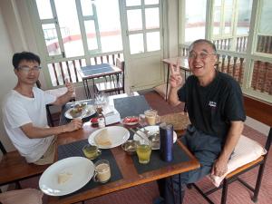 deux hommes assis à une table avec des assiettes de nourriture dans l'établissement Kaji Chen, The Tourist Accommodation, à Pātan