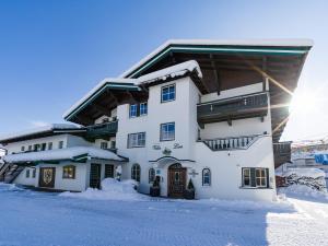 Un grand bâtiment blanc avec de la neige au sol dans l'établissement Alpen Glück Villa Lisa, à Kirchberg in Tirol