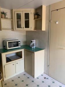 una pequeña cocina con microondas en una encimera en Comfortabele familie chalets met veranda incl airco dichtbij zee! en Viareggio
