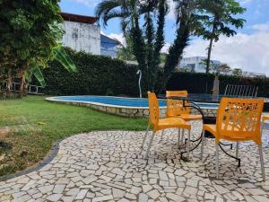 3 sillas y una mesa frente a una piscina en Casa varandas vista para o mar, en Maceió