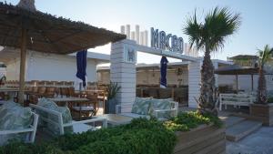 un restaurante con sillas, mesas y una palmera en Beachhouse Kokkinos Pyrgos, en Kokkinos Pirgos
