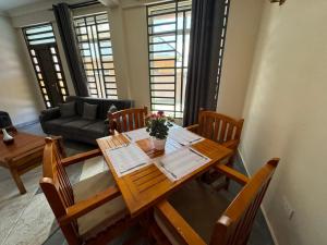 sala de estar con mesa de madera y sillas en Suji House en Dodoma