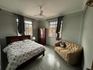 a bedroom with a bed and a couch and windows at Suji House in Dodoma