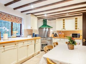 eine Küche mit weißen Schränken, einem Tisch und einem Fenster in der Unterkunft Prince Of Wales Lodge in Caston