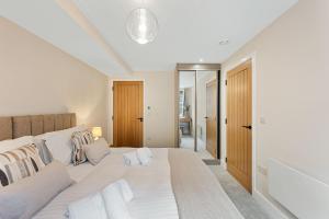 a white bedroom with a large white bed with pillows at Chatsworth Suite - Apartment 27 in Tideswell