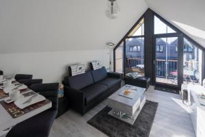 a living room with a black couch and a large window at Steife Brise in Büsum