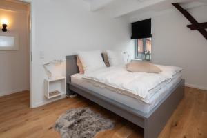 Schlafzimmer mit einem Bett mit weißer Bettwäsche und einem Fenster in der Unterkunft Feine Bleibe in Wesselburen