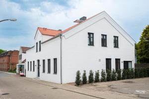 ein weißes Haus mit schwarzen Fenstern auf einer Straße in der Unterkunft Feine Bleibe in Wesselburen