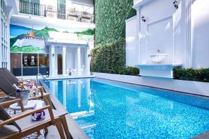 a swimming pool with chairs next to a building at Villa De Pranakorn in Bangkok