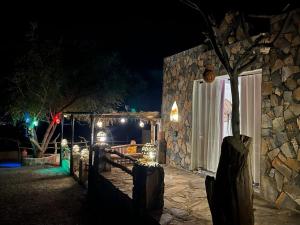 un edificio de piedra con luces en un patio por la noche en Balcony walk rest house Jabal shams, en Sa‘ab Banī Khamīs