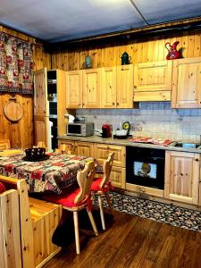 a kitchen with wooden cabinets and a table with chairs at Fionisco - Giardino privato con vista sulle Alpi in Brusson