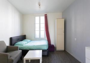 a bedroom with a bed and a couch and a window at Studio Meublé in Gentilly