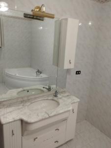 ein weißes Badezimmer mit einem Waschbecken und einem Spiegel in der Unterkunft A due passi dalle bellezze della Puglia in Sava