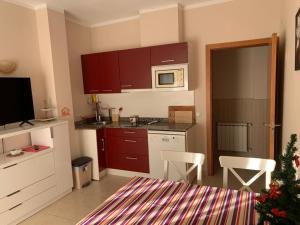 a small kitchen with red cabinets and a microwave at Casa Montgò in L'Escala