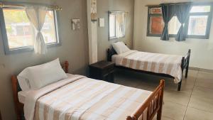 a room with two beds and two windows at Casa #344 - Habitación 3 - Full-Twin Bed - AIR CONDITIONING in Puerto Ayora
