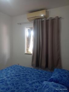 um quarto com uma cama azul e uma janela em Apt térreo perto do arena em Fortaleza