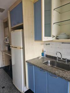 a kitchen with blue cabinets and a white refrigerator at Apartamento Parque das Rosas in Rio de Janeiro