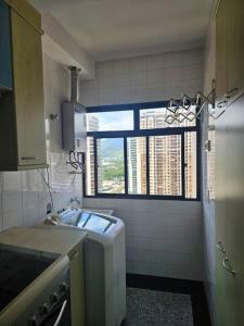 una pequeña cocina con fregadero y ventana en Apartamento Parque das Rosas, en Río de Janeiro