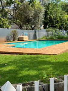 a swimming pool with a wooden deck and a fence at Zenko Suave- 12 Madison West in Johannesburg