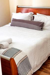 uma grande cama branca com uma cabeceira e almofadas de madeira em Zenko Suave- 12 Madison West em Joanesburgo