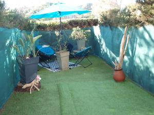 a patio with an umbrella and a cat laying on the grass at Studio le Mistral in Saint-Raphaël