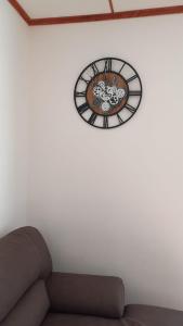 une horloge sur un mur blanc avec un canapé dans l'établissement Casa vacanza Petrari Residence Alt Air, à Ovindoli