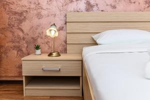 a bedroom with a bed and a nightstand with a lamp at Elite Neagoe Apartment in Braşov