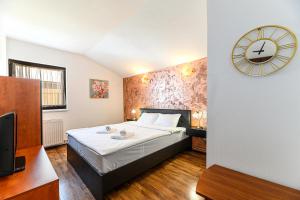 a bedroom with a bed and a clock on the wall at Elite Neagoe Apartment in Braşov