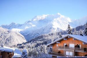 ein Haus im Schnee mit Bergen im Hintergrund in der Unterkunft Studio cabine « Au Loup Blanc » in Saint-Gervais-les-Bains