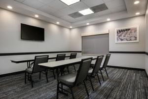 a conference room with a table and chairs and a screen at TownePlace Suites by Marriott Houston Westchase in Houston