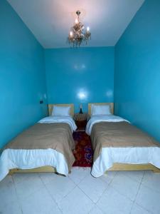 two beds in a blue room with a chandelier at Anza SurfSide House in Agadir